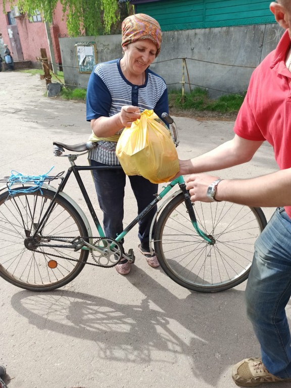 Kobieta trzymająca rower i odbierająca żywność